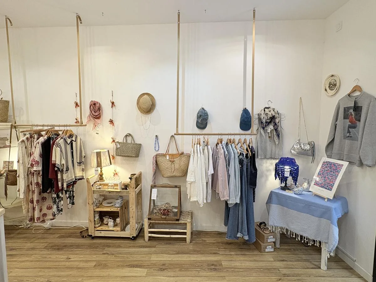 Vue en enfilade de la boutique, portants d’un côté, mobilier chiné de l’autre.