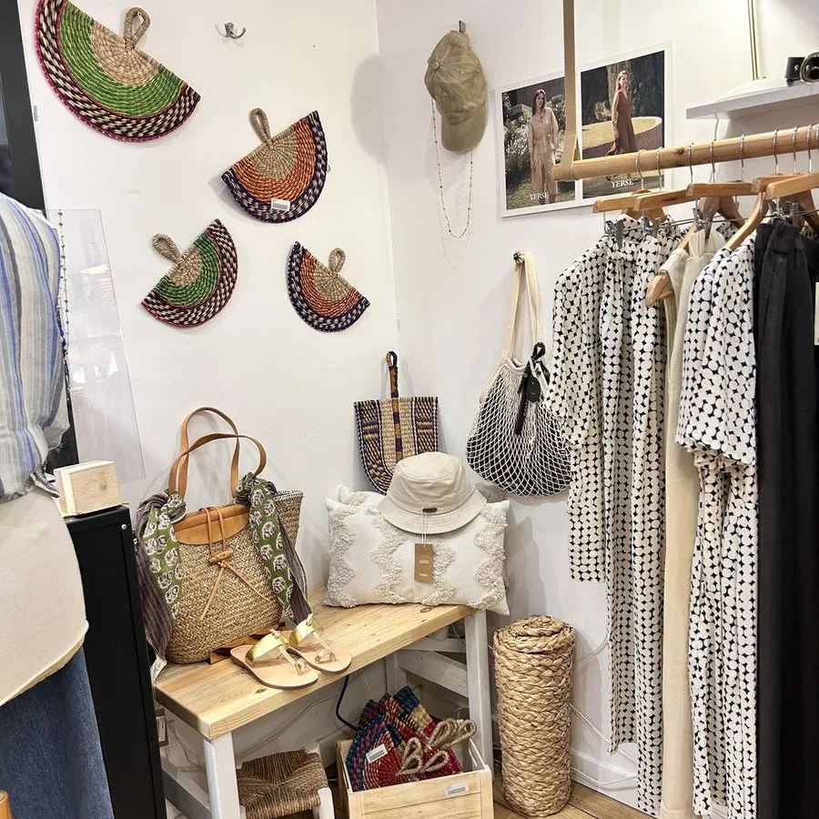 Éventails tressés accrochés en composition au mur blanc, au-dessus d’une console et d’un portant.