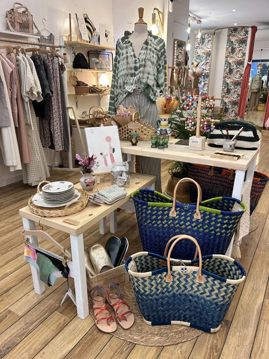 Intérieur de la boutique : parquet clair, murs blancs, portants de vêtements et mobilier chiné.