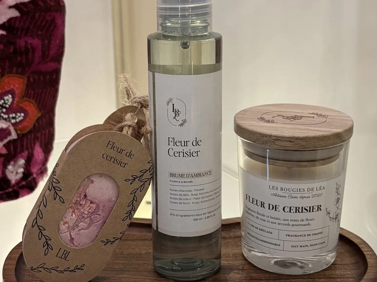 Brume d’ambiance et bougie posées sur un plateau de bois, étiquette de cire près d’elles.