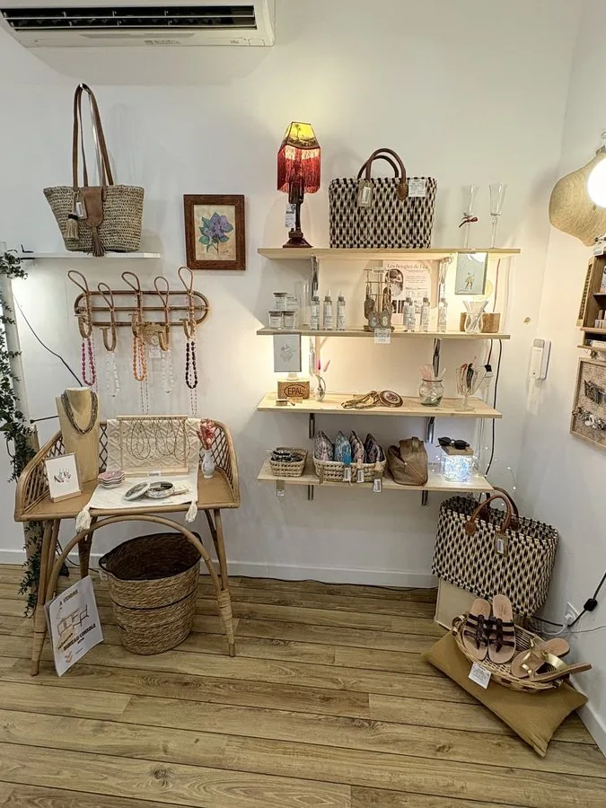 Un pan de mur d’étagères : paniers tressés, bijoux, une petite lampe rouge et des cadres.