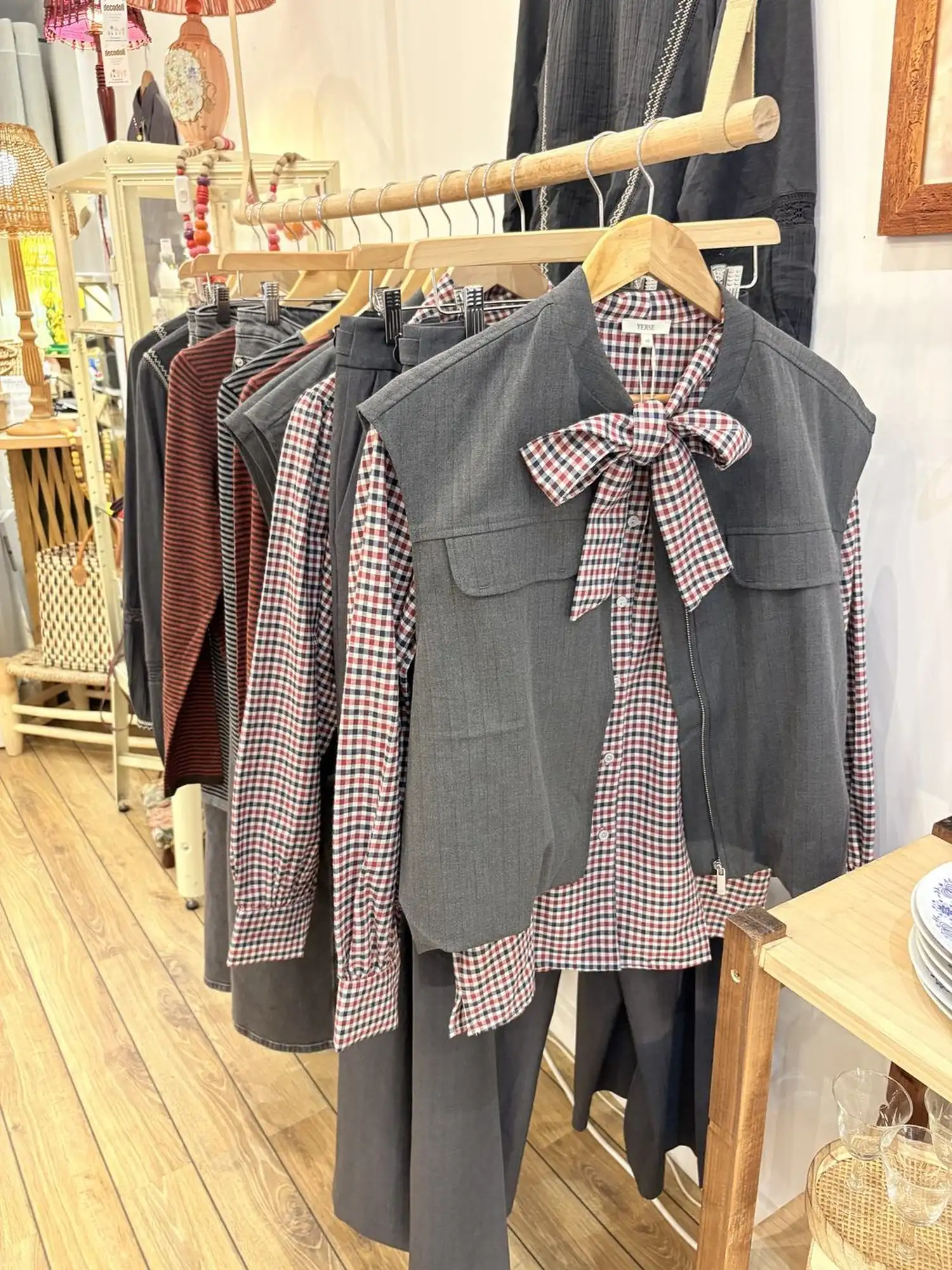 Un portant de vêtements en matières naturelles, dans la lumière de la boutique.