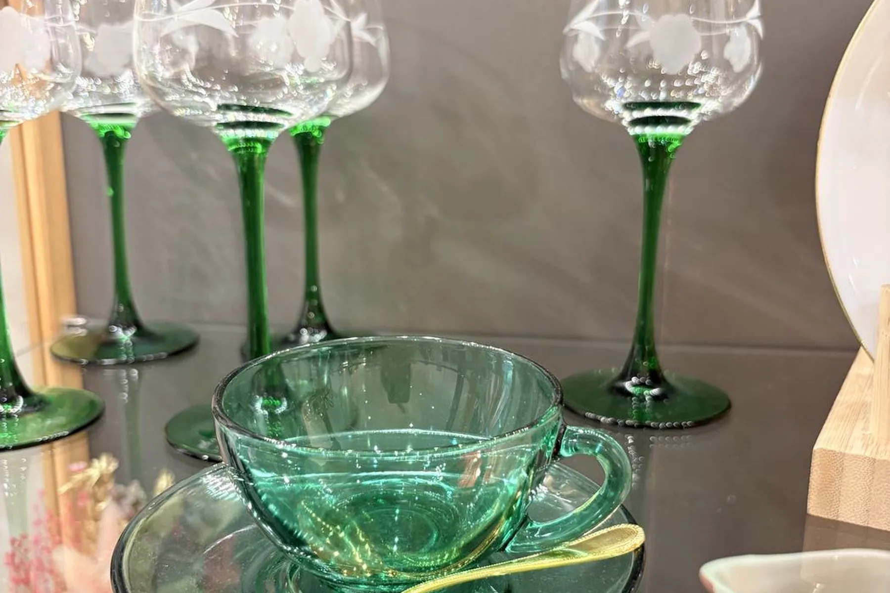 Verres à pied anciens à jambe verte et coupe en verre vert, posés sur une table de bois.
