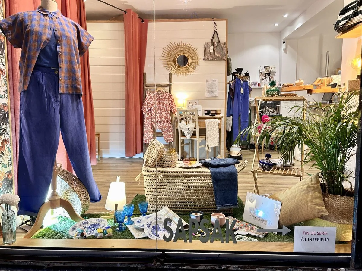 La vitrine de Sapsak vue de la rue pavée, éclairée de l’intérieur.